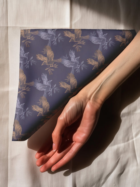 Set of four slate blue dining napkins featuring alternating gold and silver ravens in flight with botanical accents, sized 18x18 inches.